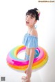 A little girl in a blue and white bathing suit holding an inflatable ring.