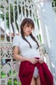 A woman in a white shirt and red skirt posing for a picture.