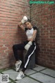 A woman wearing boxing gloves leaning against a brick wall.