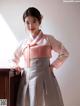 A woman in a pink and gray hanbok posing for a picture.