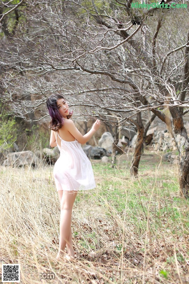 A woman in a white dress standing in a field.