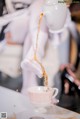 A person pouring tea into a cup on a table.