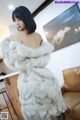 A woman in a white fur coat standing in a living room.