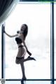 A woman in lingerie posing in front of a window.