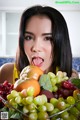 A woman sticking out her tongue in front of a bowl of fruit.