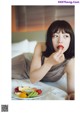 A woman laying on a bed eating a plate of fruit.