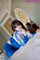 A woman in a blue and white outfit sitting on a bed.