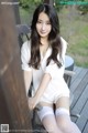 A woman in a white shirt and white stockings sitting on a chair.