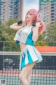 A woman with pink hair standing on a tennis court.